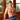 Man wearing blue underwear sitting in a room with wooden walls and plants.