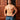 Man wearing blue patterned underwear standing against a wooden door.