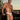 Man wearing colorful tanga briefs standing outdoors with a sunset background