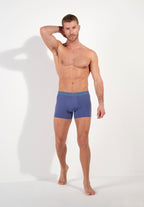 Man wearing blue boxer briefs on a white background