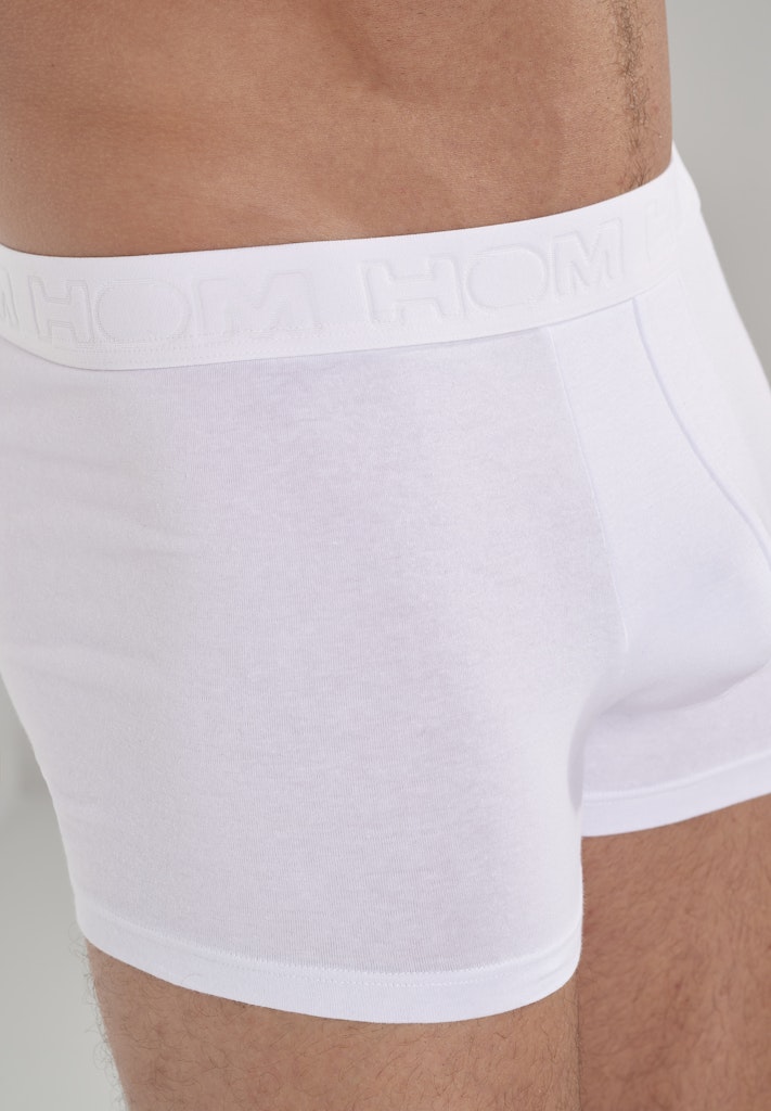 White boxer briefs worn by a person with a neutral background
