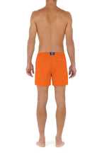 Person wearing bright orange swim shorts on a white background