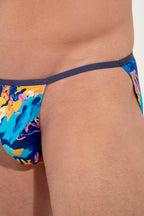 Colorful tanga briefs with abstract design on a person against a neutral background