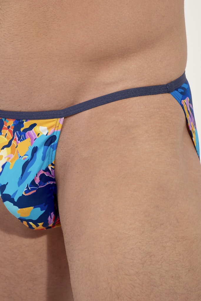 Colorful tanga briefs with abstract design on a person against a neutral background