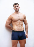 Man wearing navy blue boxer briefs against a white background