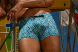 Person wearing blue patterned swim shorts with a blurred background