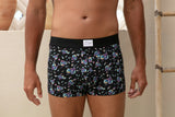 Person wearing black boxer briefs with colorful pattern in a bathroom setting