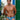 Man wearing blue patterned swim trunks standing in front of a white wall with green accents.