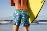 Person holding a yellow surfboard on a beach with ocean waves in the background