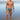 Man standing on a beach wearing patterned swim trunks with ocean waves in the background
