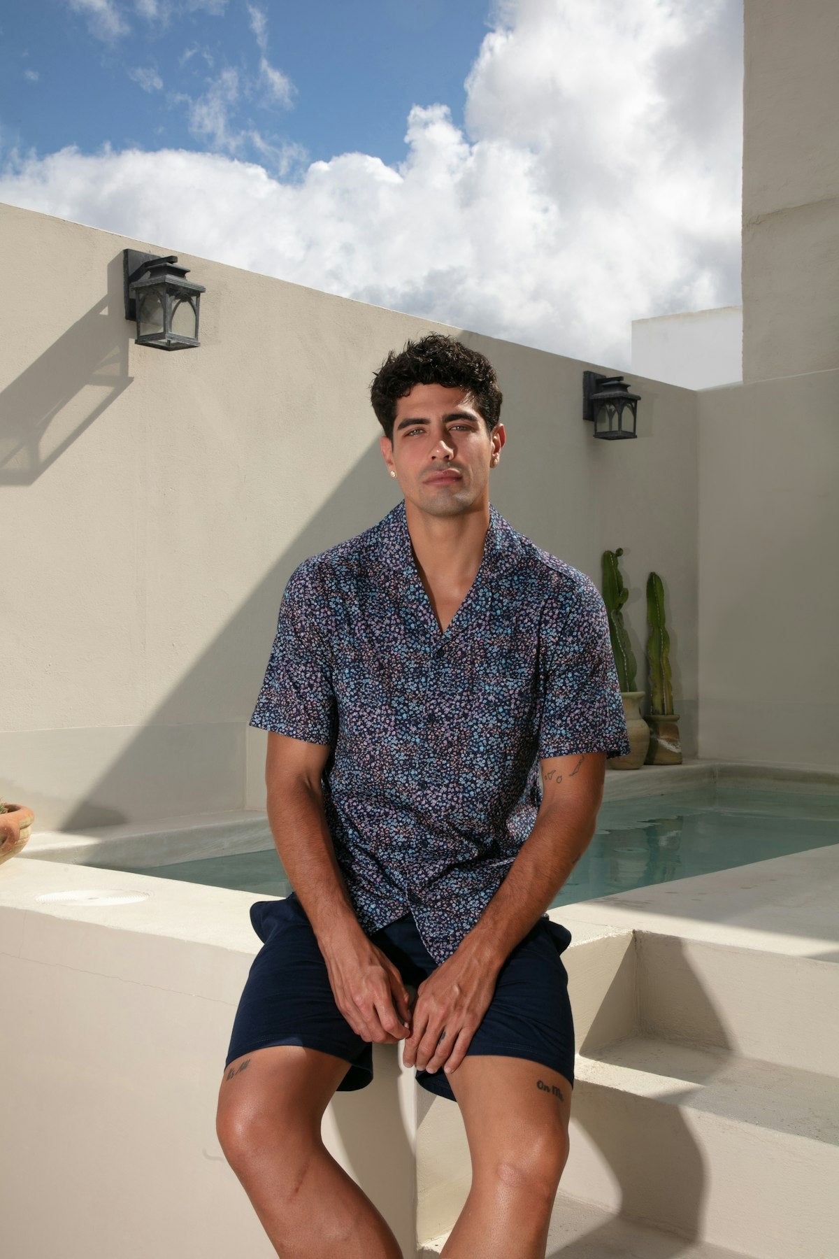 Man sitting by a pool with a cactus in the background
