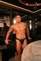 Man wearing black underwear in a dimly lit room with marble table