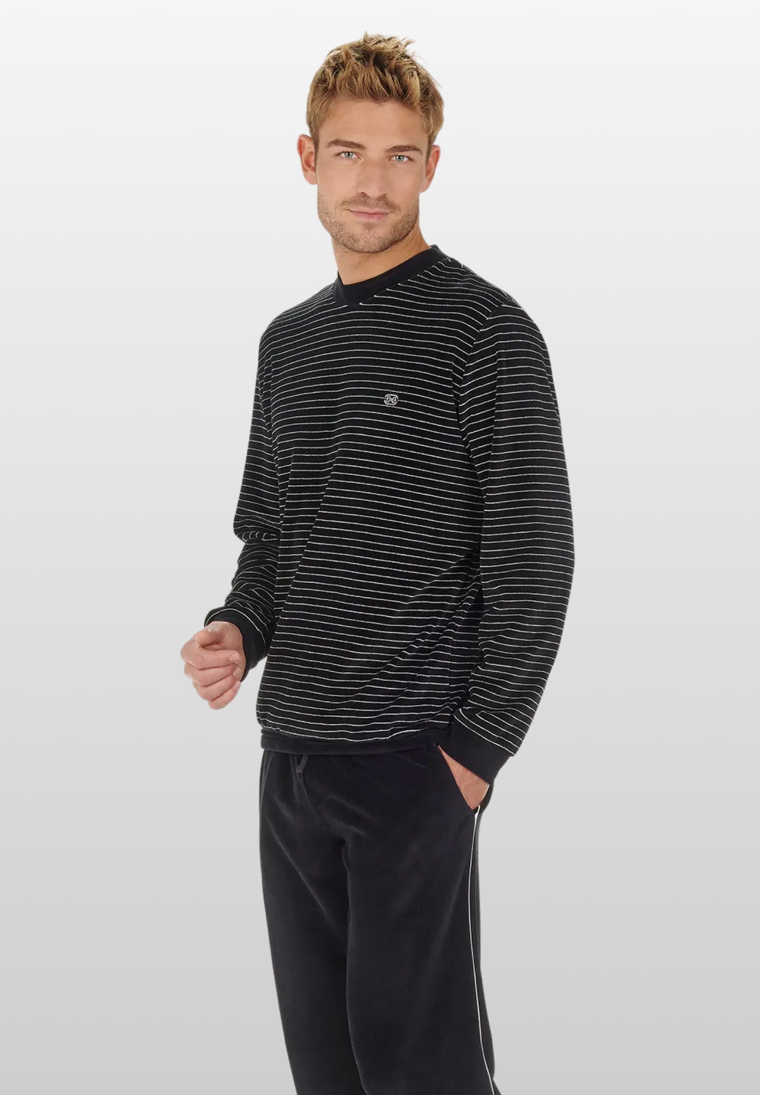 Man wearing a black and gray striped long-sleeve shirt and black pants on a light gray background